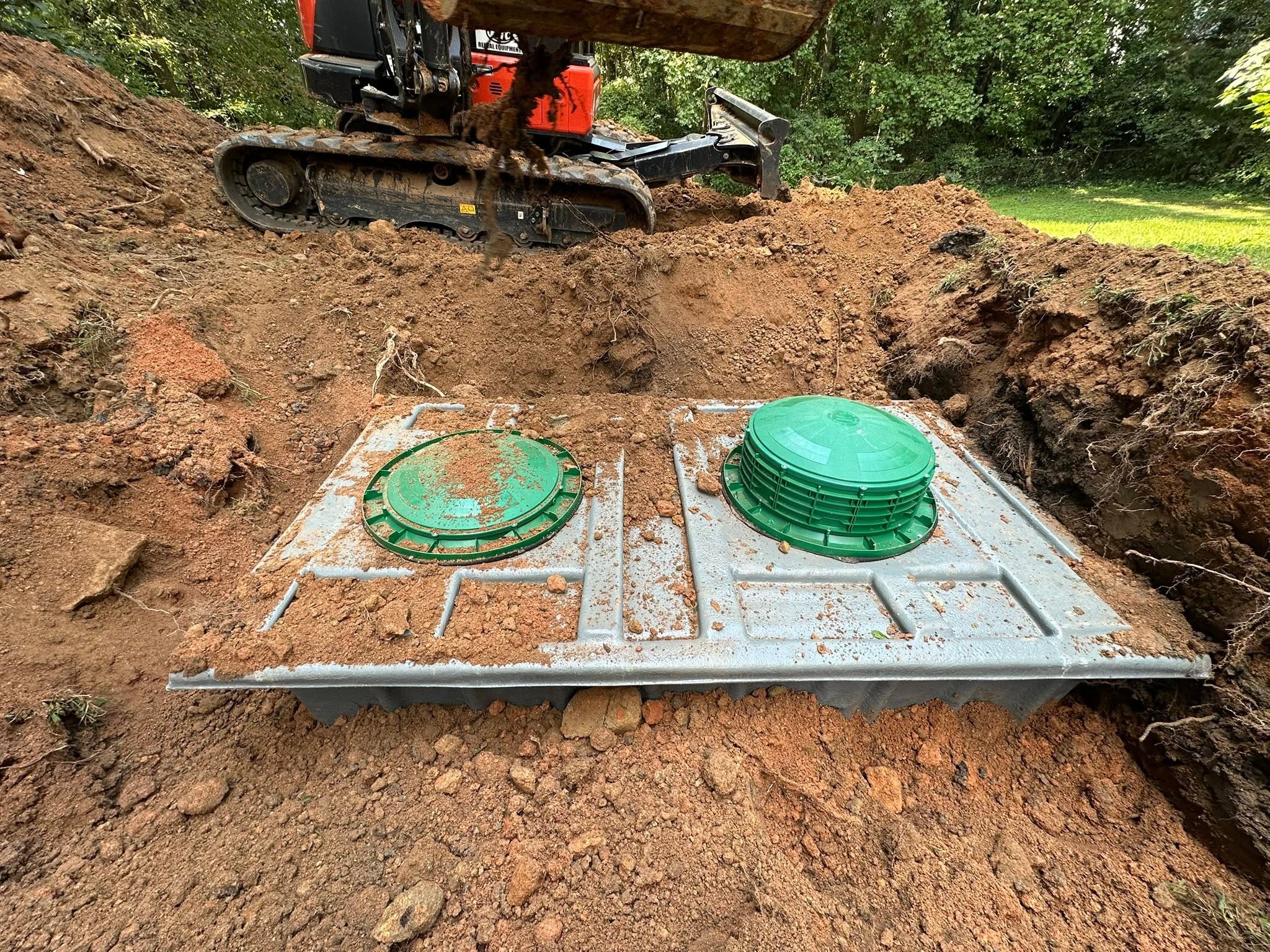 Concrete septic tank with two green access lids during installation
